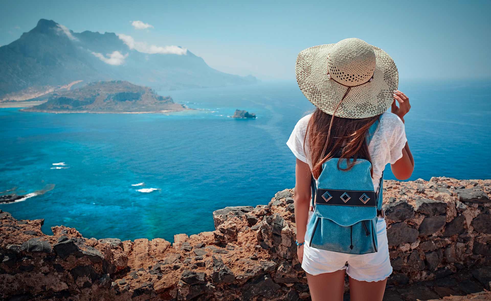 Woman standing on a cliff edge looking out across the ocean